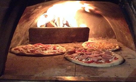 pizza being cooked in a wood fire oven